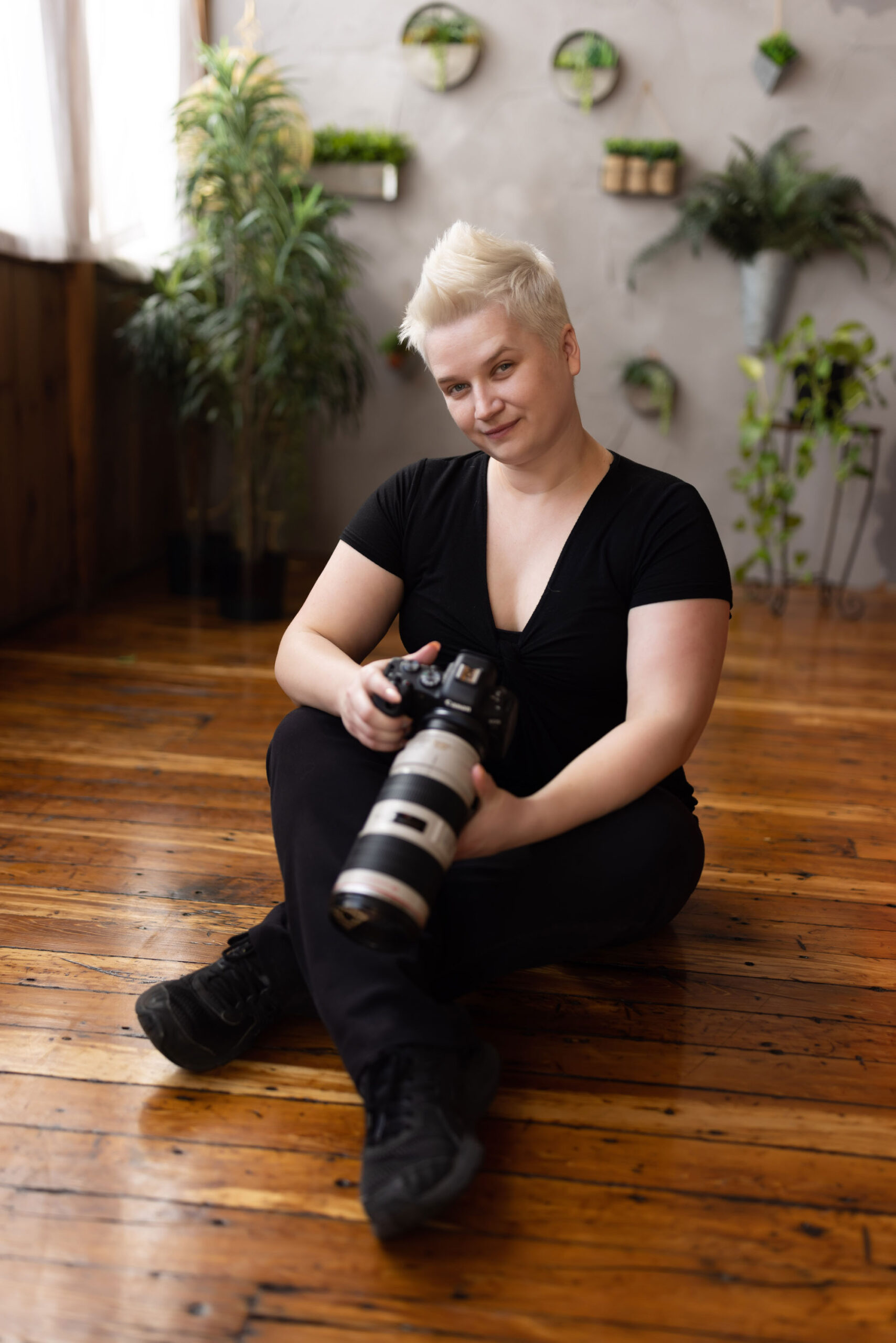 Portrait of Jessie Clements, photographer at Boudoir by J&S Photography based in Shirley, Massachusetts, holding a digital camera with zoom lens in her photo studio