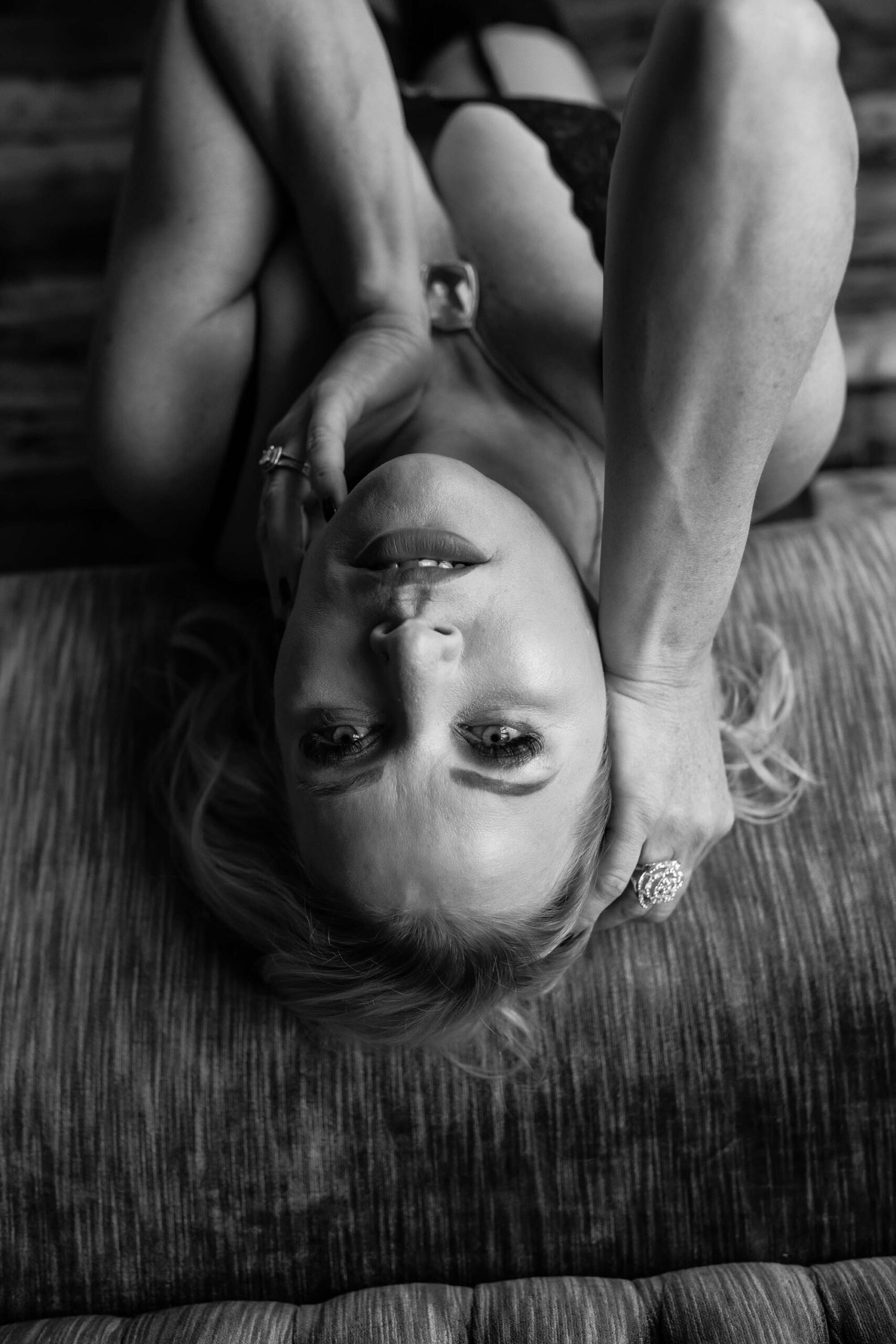 black and white boudoir photo of a blonde woman wearing black lingerie leaning back on a vintage couch in the Boudoir by J&S Photography studio near Boston, Massachusetts