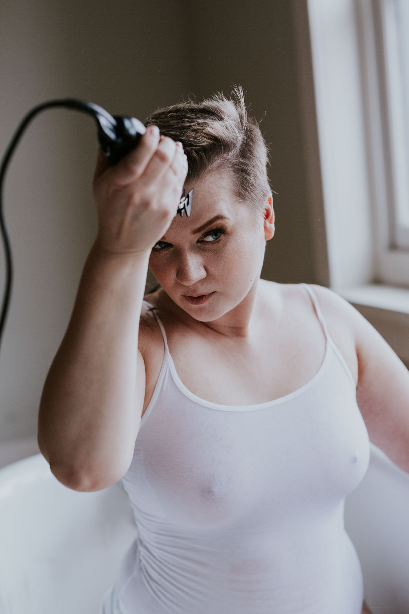 Jessie Clements shaving her head in a white tub in Teri Hofford's boudoir studio